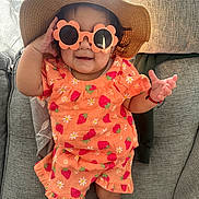 Haisley joined the competition — help win amazing prizes! toddler, child, sunglasses, hat, orange_clothing, strawberry_pattern, smile, couch, indoor, happy, baby, bracelet, shorts, shirt, person, furniture, cute, playful, sunhat, glasses