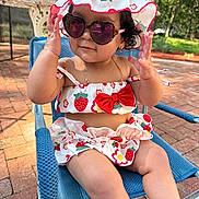 Haisley is registered to the contest to win money with this photo: accessories, armchair, blue_chair, child, clothing, cute, fashion, happy, hat, legs, nature, outdoor, person, portrait, smiling, strawberry_pattern, summer, sunglasses, sunlight, toddler