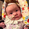 baby, infant, child, portrait, lying_down, headband, floral_dress, ruffle, feeding_tube, medical_tape, face, eyes, indoors, cushion, floral_pattern, colorful, close_up, infant_care, hospital_equipment, adorable