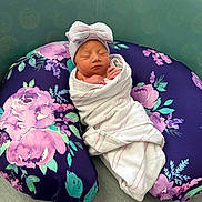 Aubree joined the competition — help win amazing prizes! newborn, baby, swaddle, hat, bow, sleeping, pillow, floral, purple, striped, cute, peaceful, resting, soft, green, background, infant, child, portrait, cozy