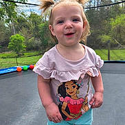 Trenity is registered to the contest to win money with this photo: toddler, child, pigtails, smiling, trampoline, outdoor, basketball_hoop, greenery, shorts, shirt, cartoon_character, daylight, play, happy, nature, grass, trees, person, young_child, summer_clothing