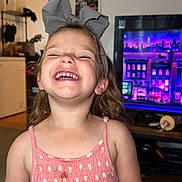 Avianna is registered to the contest to win money with this photo: child, girl, smiling, laughing, bow, headband, pink_dress, indoors, television, colorful, living_room, happy, cute, portrait, person, home, fun, young_child, casual, bright