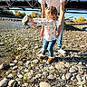 Avianna joined the competition — help win amazing prizes! child, adult, river, rocks, bridge, outdoor, sunny, casual_clothing, jeans, white_shirt, nature, water, smile, curly_hair, play, fun, helping, trees, grass, daylight