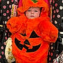 baby, pumpkin_costume, orange, stroller, polka_dot, infant, cute, halloween, costume, child, plush, seat, pattern, face, hood, leaf, black, pink, white, expression
