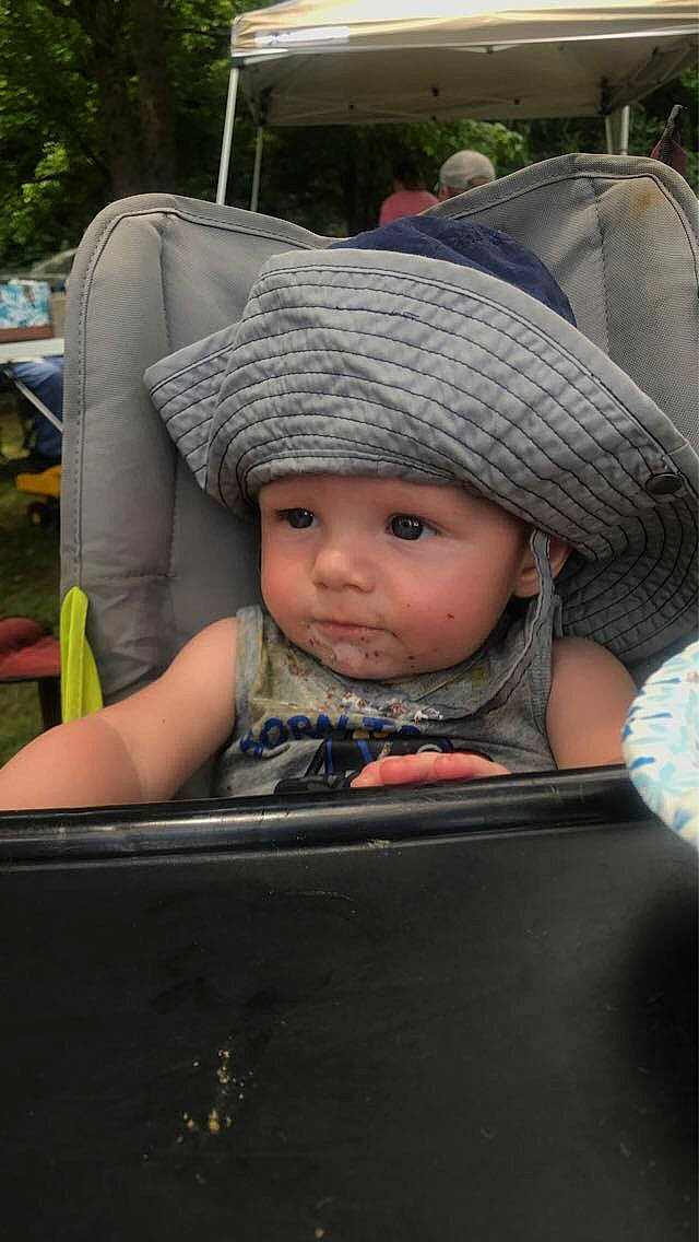 Eli is registered to the contest to win money with this photo: auto_part, automotive_exterior, baby, baby_carriage, baby_products, cap, chair, child, family_car, fashion_accessory, fun, grass, hat, headgear, headwear, person, plant, sitting, toddler, tree