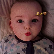Noah is registered to the contest to win money with this photo: baby, infant, face, pajamas, stars, expression, cute, lying_down, pillow, bed, indoors, child, person, sleepwear, cozy, head, skin, mouth, eyes, adorable