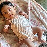 Amora joined the competition — help win amazing prizes! baby, infant, blanket, pink, striped_onesie, face, skin, hand, foot, lying_down, carpet, couch, soft_texture, child, newborn, indoors, relaxed, cute, small, person