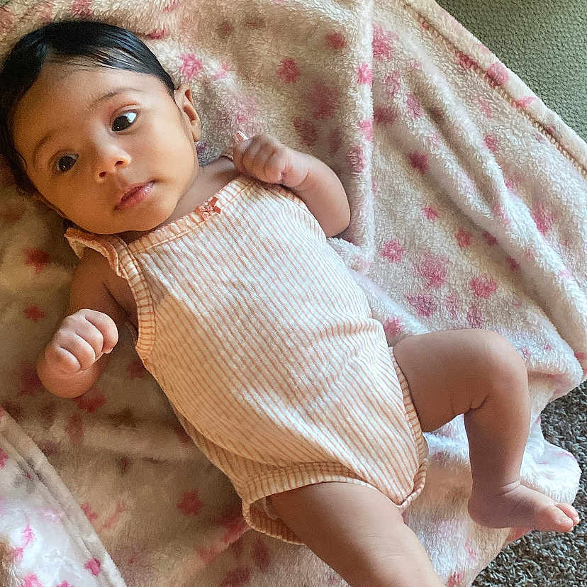 Amora joined the competition — help win amazing prizes! baby, blanket, carpet, child, couch, cute, face, foot, hand, indoors, infant, lying_down, newborn, person, pink, relaxed, skin, small, soft_texture, striped_onesie