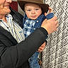 adult, baby, blue_eyes, boots, child, clothing, cowboy_hat, curtain, cute, denim_jacket, family, fashion, hat, holding, indoor, pattern, person, plaid_shirt, portrait, smile