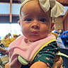 baby, background, blurred, bow, child, closeup, cute, expression, face, green_clothing, hand, headband, holding, indoor, infant, people, person, pink_bib, portrait, wooden_beams