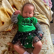 Ahvi Princess is registered to the contest to win money with this photo: baby, sleeping, green_clothing, striped_sleeves, tutu, stars, blanket, couch, floral_pattern, cozy, infant, white_socks, indoors, resting, cute, child, festive, holiday, comfort, soft_fabric