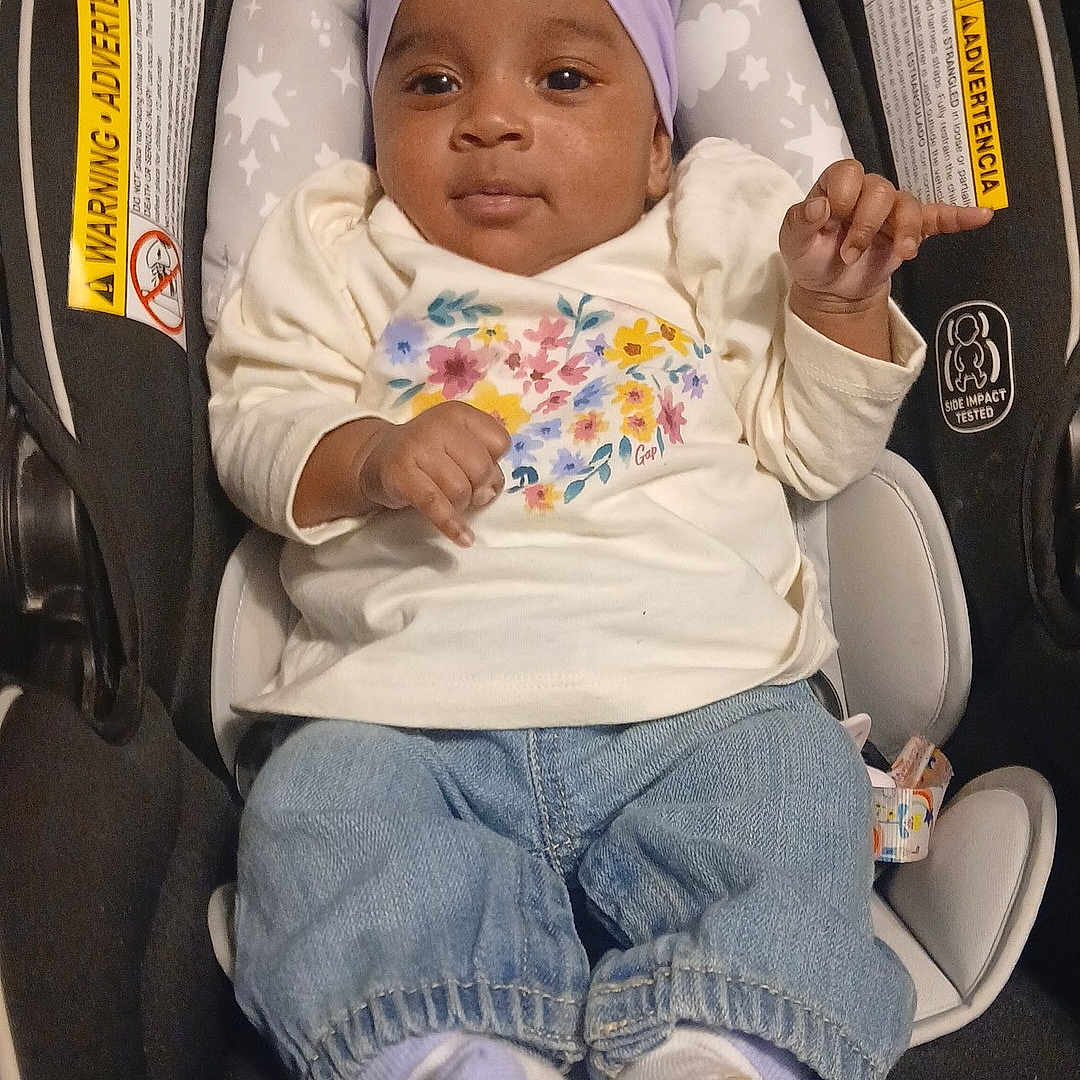 Gazzelle is registered to the contest to win money with this photo: baby, car_seat, child, clothing, cute, denim, floral, footwear, headband, indoors, infant, pants, portrait, purple, safety, seat, shirt, smile, socks, young