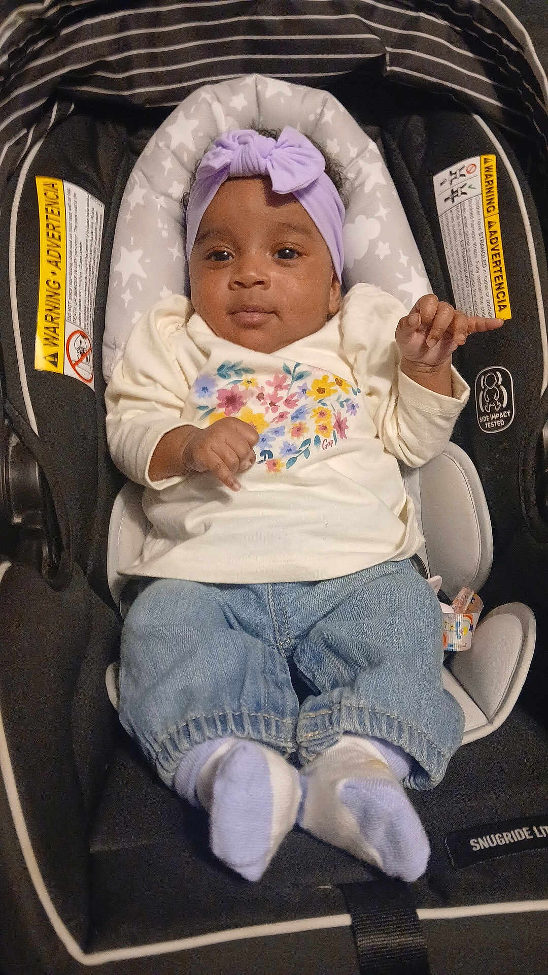Gazzelle is registered to the contest to win money with this photo: baby, child, infant, car_seat, headband, purple, clothing, floral, shirt, denim, pants, socks, footwear, indoors, seat, safety, smile, portrait, cute, young