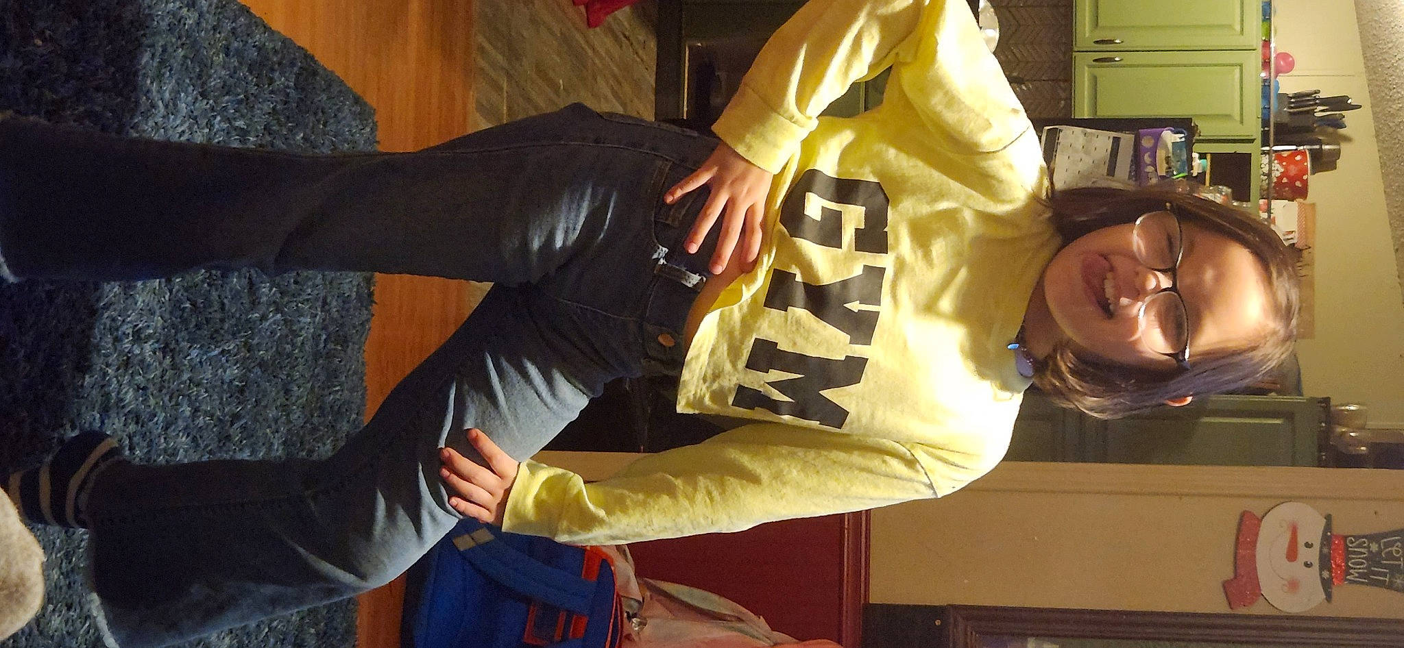 Skylar is registered to the contest to win money with this photo: bookcase, elbow, event, fun, human_body, human_leg, knee, person, room, shelf, shelving, sitting, sleeve, smile, sportswear, t_shirt, thigh, wrist