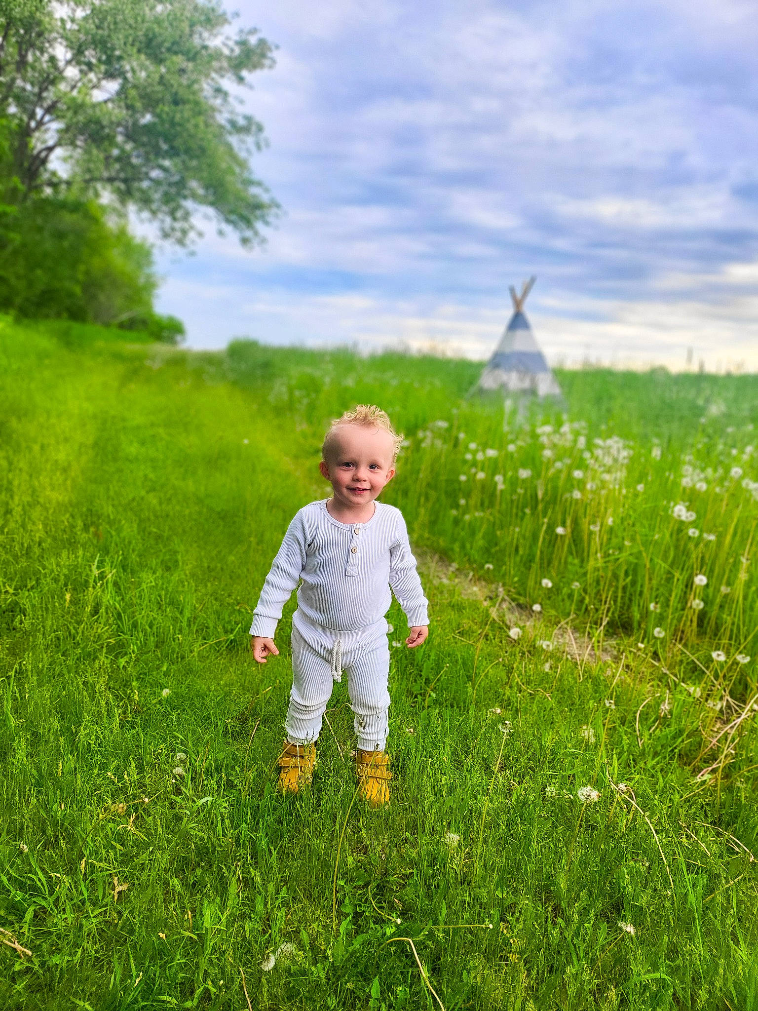 Finn is registered to the contest to win money with this photo: baby_toddler_clothing, cloud, flower, gesture, grass, grass_family, grassland, green, happy, joy, landscape, meadow, natural_landscape, pasture, people_in_nature, person, plant, prairie, sky, summer