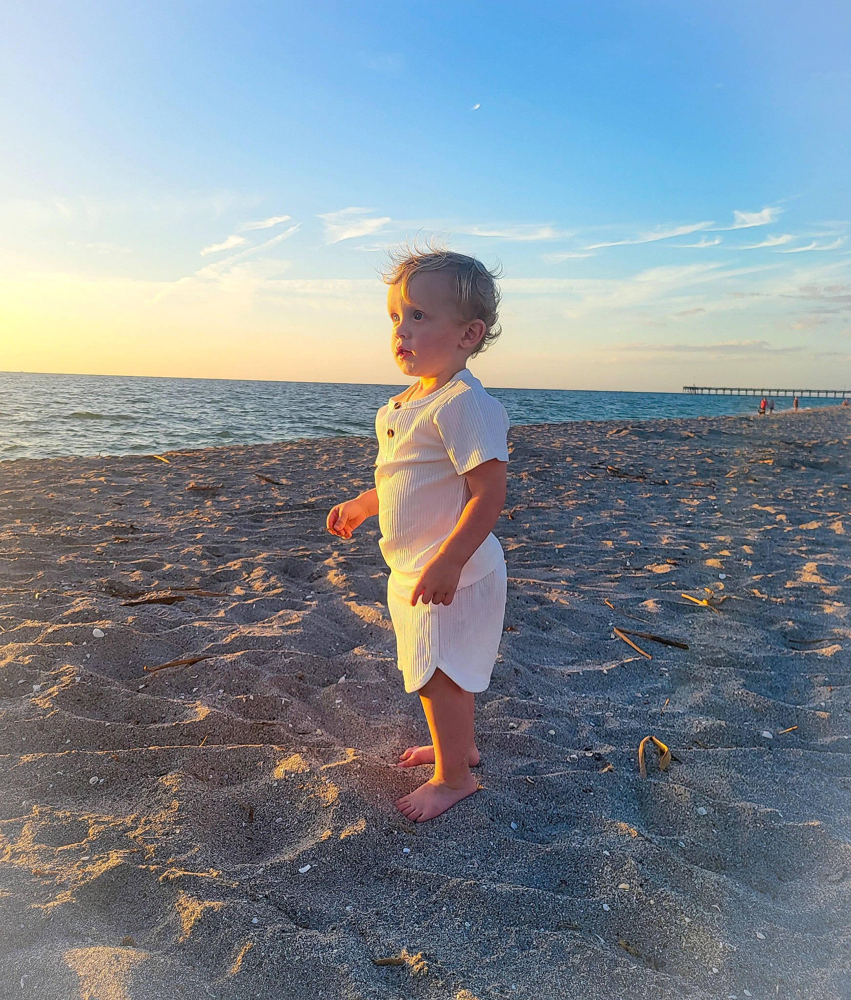 Finnley joined the competition — help win amazing prizes! beach, calm, cloud, coastal_and_oceanic_landforms, dusk, flash_photography, fun, gesture, happy, horizon, landscape, people_in_nature, people_on_beach, person, sky, standing, sunlight, toddler, travel, water