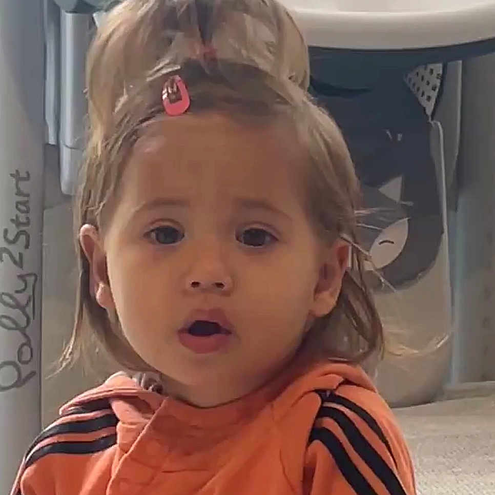 Lana a rejoint le concours — aidez-le/la à gagner de superbes lots ! cartoon_background, casual, child, closeup, clothing, cute, expression, face, floor, hair, hair_clip, indoor, orange_jacket, person, portrait, surprised, toddler, toy, young_child, young_person