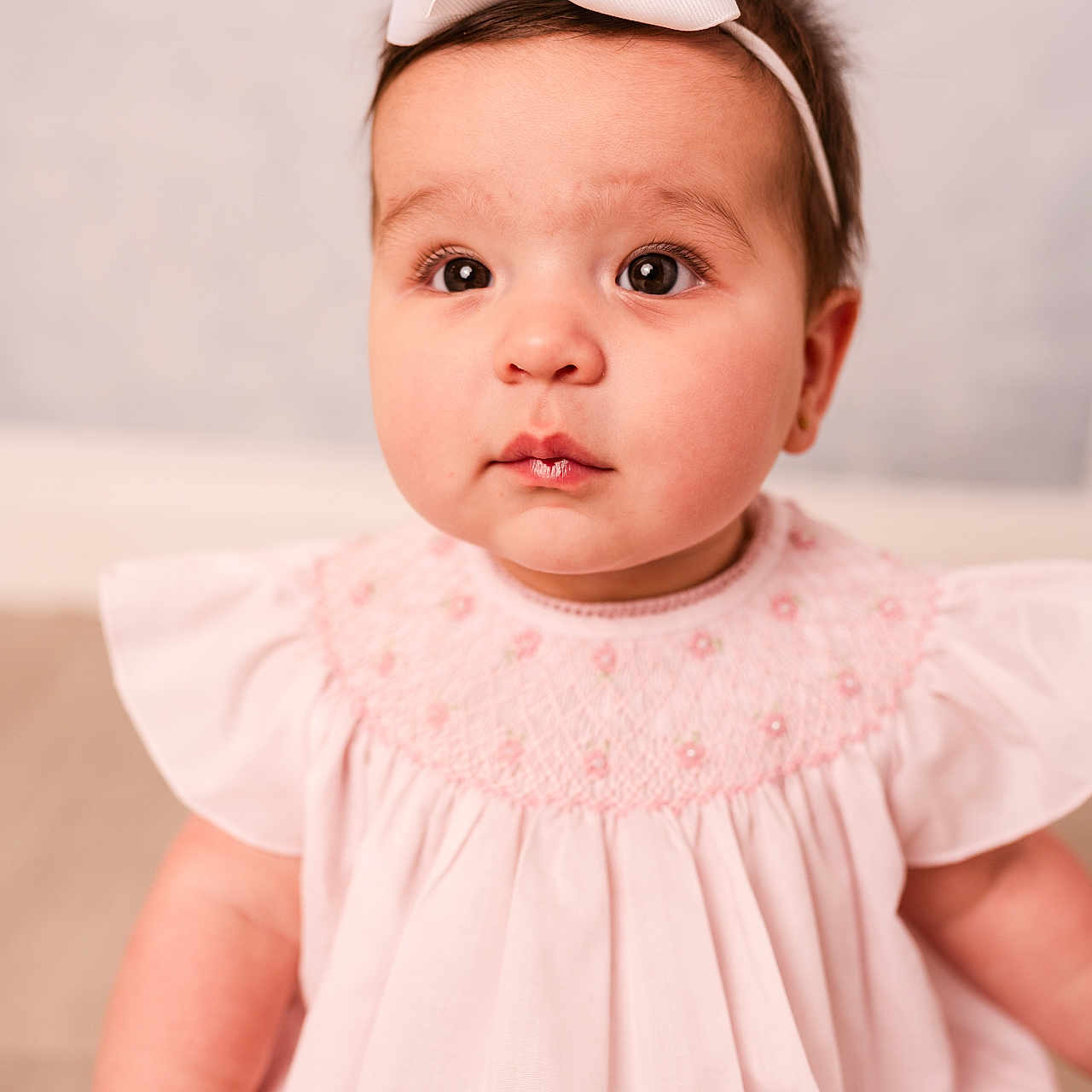 Emerson joined the competition — help win amazing prizes! adorable, baby, child, closeup, curious_eyes, cute, face, girl, headband, indoor, infant, innocent_expression, pink_dress, portrait, ruffled_sleeves, sitting, skin, soft_lighting, white_bow, young_child