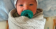 Melo is registered to the contest to win money with this photo: baby, newborn, pacifier, blanket, hat, infant, wrapped, cozy, soft, pillow, lying_down, closeup, cute, indoors, sleeping_area, child, face, portrait, resting, comfort