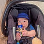 baby, car_seat, toy, blue_cap, infant, child, indoor, floor_tile, cleaning_tools, hands, clothing, seatbelt, curious, sitting, cute, person, face, playful, childhood, young
