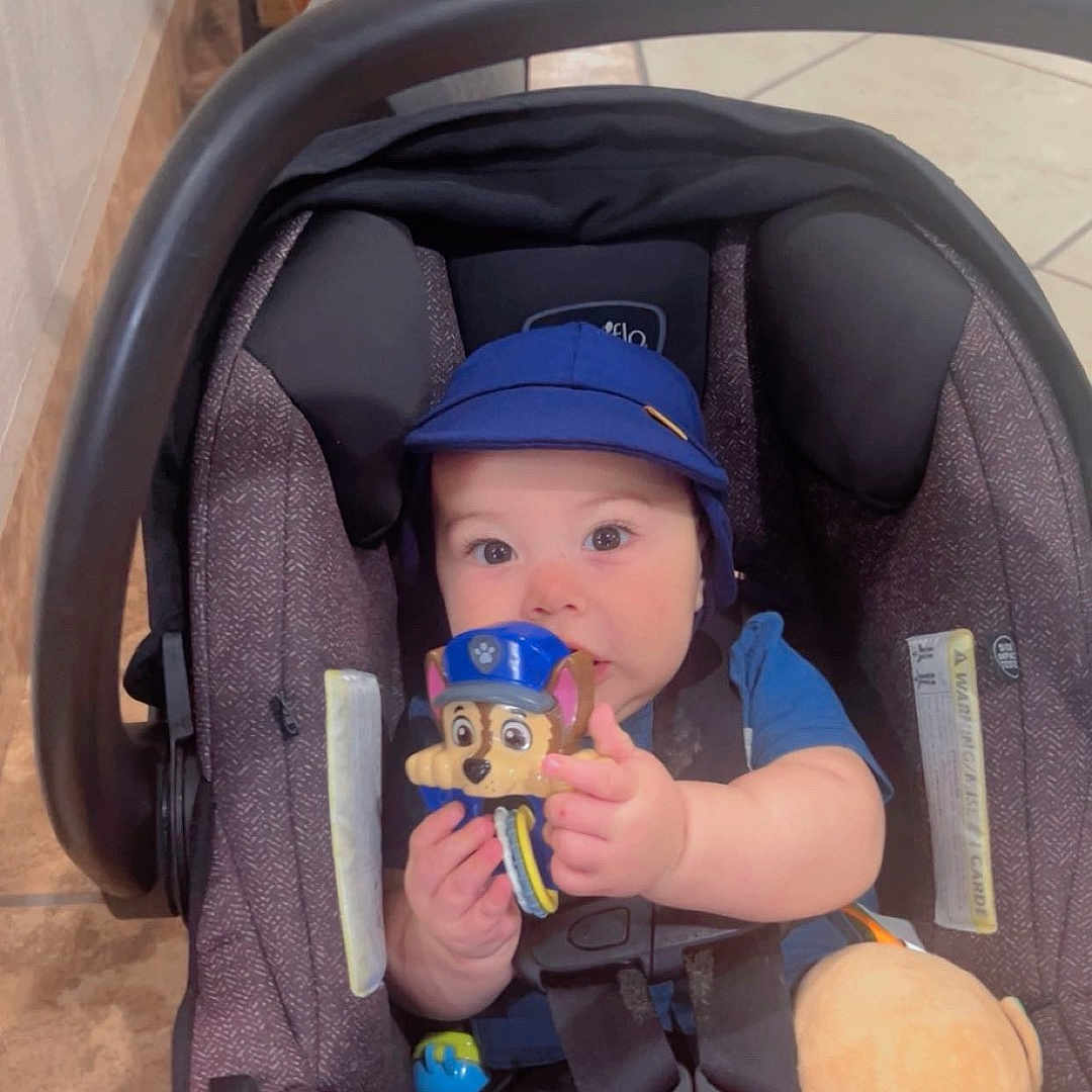 Eliette is registered to the contest to win money with this photo: baby, blue_cap, car_seat, child, childhood, cleaning_tools, clothing, curious, cute, face, floor_tile, hands, indoor, infant, person, playful, seatbelt, sitting, toy, young