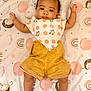 baby, infant, child, blanket, polka_dot, bib, shorts, lying_down, cute, indoors, patterned_blanket, face, arms, legs, head, expression, soft_lighting, colorful, clothing, portrait