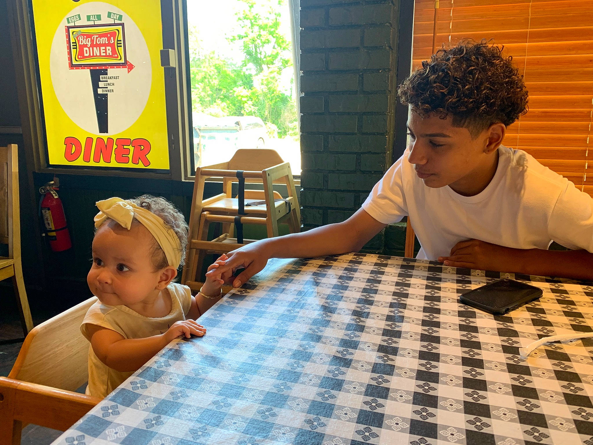 Nevaeh is registered to the contest to win money with this photo: chair, child, event, flooring, fun, hardwood, indoor_games_and_sports, leisure, pattern, person, recreation, room, sharing, sitting, t_shirt, table, toddler, tree, vacation, window