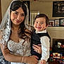 bride, wedding_dress, veil, child, toddler, smile, portrait, indoor, person, holding, happy, toy, living_room, furniture, photography, ring, phone, lace, clothing, family