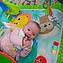 baby, infant, playmat, toy, smiling, happy, child, colorful, cartoon, animal, fabric, hand, clothing, bib, playtime, indoors, cute, young, face, expression