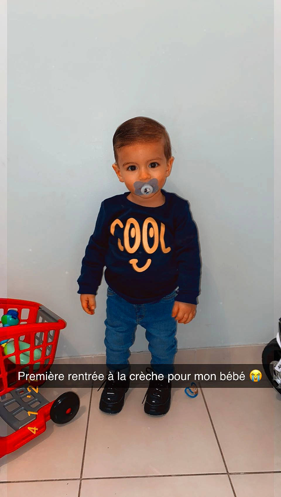 Keylian participe au concours pour gagner de l'argent avec cette photo : baby, baby_toddler_clothing, carmine, chair, child, denim, electric_blue, floor, flooring, font, gadget, hairstyle, jeans, pattern, person, sleeve, sportswear, standing, t_shirt, toddler