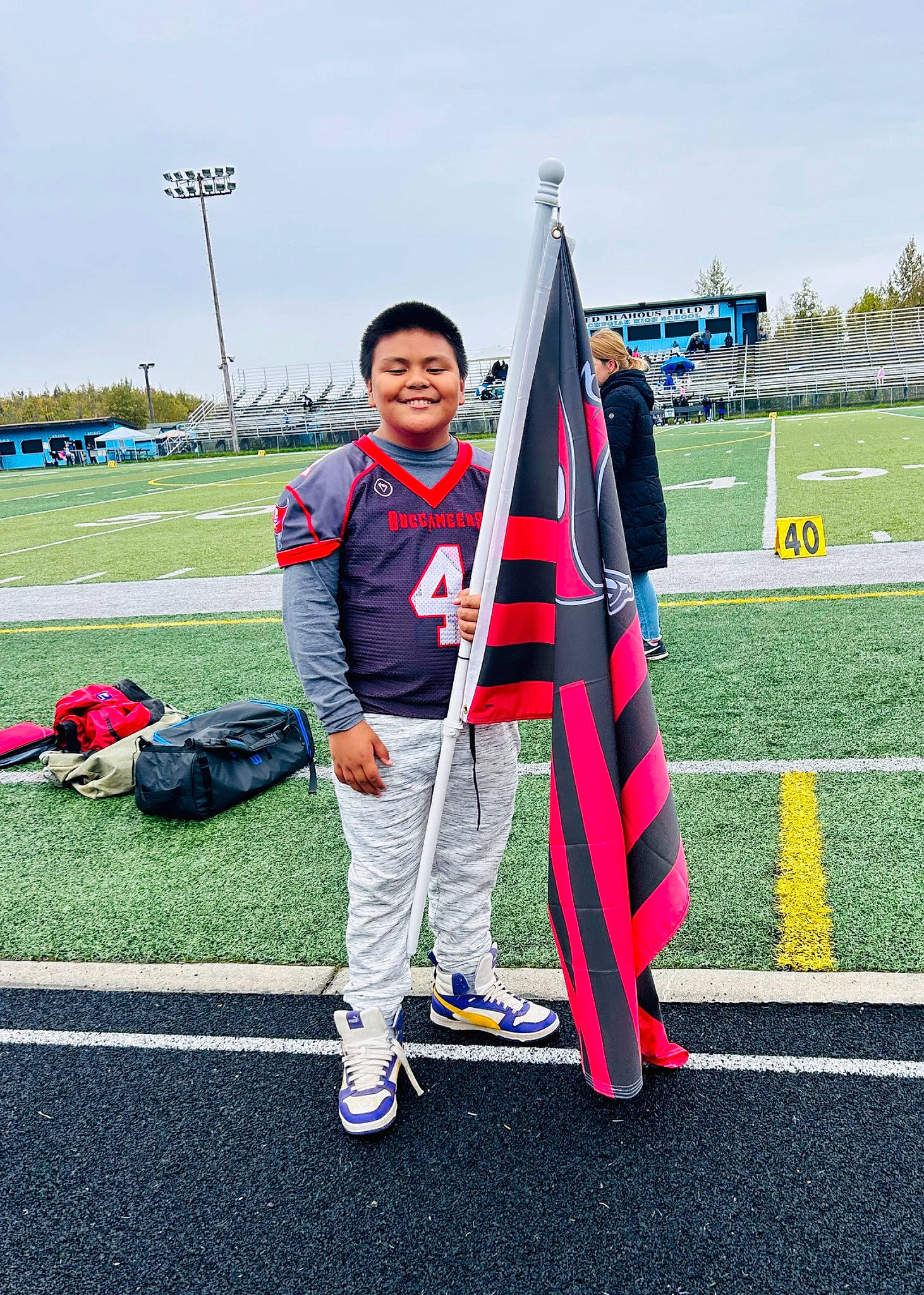 Aiden is registered to the contest to win money with this photo: asphalt, backpack, cloud, competition_event, cone, event, flag, flag_of_the_united_states, fun, grass, grassland, joy, leisure, luggage_and_bags, person, pole, recreation, sky, smile, sports