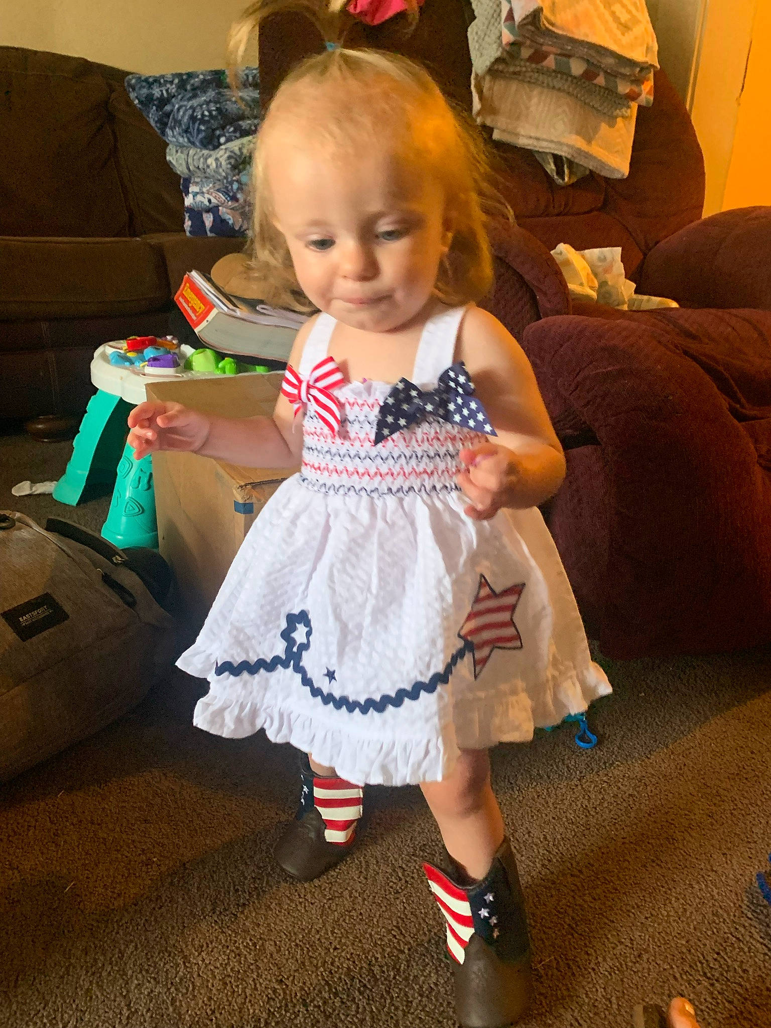 Dakota is registered to the contest to win money with this photo: baby_toddler_clothing, child, comfort, couch, dress, event, face, flooring, fun, hair, happy, head, human_leg, iris, lamp, person, room, sitting, smile, sock