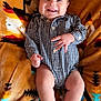 baby, infant, smiling, lying_down, blanket, patterned_blanket, checkered_clothing, onesie, happy, cute, child, skin, foot, hand, face, head, indoor, cozy, soft_texture, playful