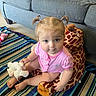 Allison is registered to the contest to win money with this photo: baby, carpet, child, cute, feet, giraffe, home, indoor, living_room, person, pigtails, pink_clothing, plush_toy, sitting, smiling, sofa, striped_rug, stuffed_animal, toddler, toy