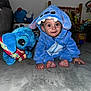 Sandro participe au concours pour gagner de l'argent avec cette photo : baby, child, costume, blue, plush_toy, carpet, indoor, cute, smile, crawling, toy, stuffed_animal, face, person, clothing, hood, home, playroom, curious, childhood
