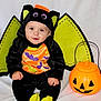 Sandro participe au concours pour gagner de l'argent avec cette photo : baby, child, costume, halloween, bat_wings, pumpkin_bucket, orange, black, green, cute, smiling, sitting, indoors, holiday, festive, face, headwear, clothing, toy, happy