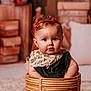 baby, infant, child, basket, headband, red_flower, face, blue_eyes, clothing, lace, sequins, portrait, indoor, cozy, warm_lighting, wooden_background, decor, cute, sitting, expression