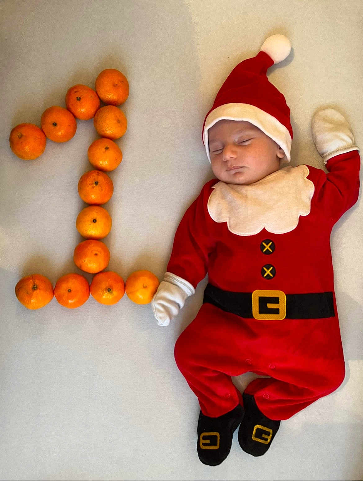 Serafin participe au concours pour gagner de l'argent avec cette photo : baby, sleeping, santa_claus_costume, tangerines, number_one, orange, infant, holiday, festive, cute, lying_down, soft_surface, gloves, hat, face, child, one, footwear, red_clothing, white_background