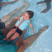 Dasean is registered to the contest to win money with this photo: baby, child, water, pool, swimming, floatation_vest, adult, legs, arms, blue, orange, swimwear, water_ripples, outdoor, summer, skin, person, holding, relaxing, safety