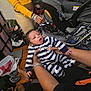 Kamarion Swinger is registered to the contest to win money with this photo: baby, infant, striped_onesie, hands, car_seat, yellow_sweatshirt, bracelets, indoor, bedroom, diaper_bag, slippers, wooden_floor, person_holding_baby, cuddling, young_child, casual_photo, family_scene, bag, clutter, yawning