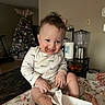 Jonah is registered to the contest to win money with this photo: blanket, child, chocolate, christmas_tree, cozy, curly_hair, face, floral, happy, holiday, home, indoor, messy, person, playful, sitting, smiling, snack, table, toddler
