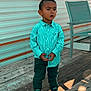 Ezai a rejoint le concours — aidez-le/la à gagner de superbes lots ! child, toddler, boy, standing, shirt, pants, shoes, outdoor, deck, wood, sunlight, shadow, trailer, window, chair, curious, expression, casual_clothing, daylight, person