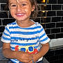 toddler, child, smiling, happy, striped_shirt, crab_illustration, pacifier, kitchen, counter, black_tiles, shorts, indoor, cute, portrait, young_child, casual_clothing, playful, holding, seated, bright_lighting