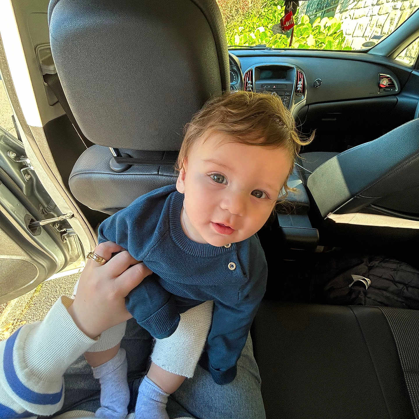 Enis participe au concours pour gagner de l'argent avec cette photo : baby, blue_sweater, car_interior, casual_clothing, child, curly_hair, cute, hand, human, indoor, lap, looking_at_camera, open_car_door, person, portrait, seat, seated, socks, sunlight, young_child
