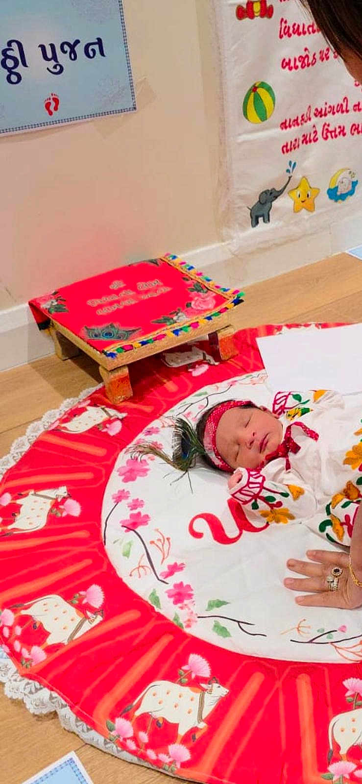 Krish joined the competition — help win amazing prizes! newborn, baby, sleeping, colorful_clothing, headband, traditional_attire, mat, floor, decorative_stool, hand, rings, poster, text, wall, wooden_floor, flower_pattern, animal_pattern, indoors, child, peaceful