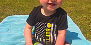 Quinn joined the competition — help win amazing prizes! baby, barefoot, black_clothing, blue_towel, bow, child, cute, daylight, grass, happy, headband, nature, outdoor, person, play, sitting, smiling, sunny, toddler, toy
