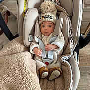 Tiago participe au concours pour gagner de l'argent avec cette photo : baby, blanket, boots, bundle, car_seat, child, cozy, cute, expression, face, flooring, hat, indoor, infant, knitwear, mickey_mouse, person, straps, warm, wood_floor