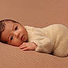 Tiago participe au concours pour gagner de l'argent avec cette photo : baby, brown_background, cozy, cream_color, cute, expression, eyes, face, hand, infant, knitwear, lying_down, newborn, peaceful, portrait, resting, skin, soft_texture, warm, young_child