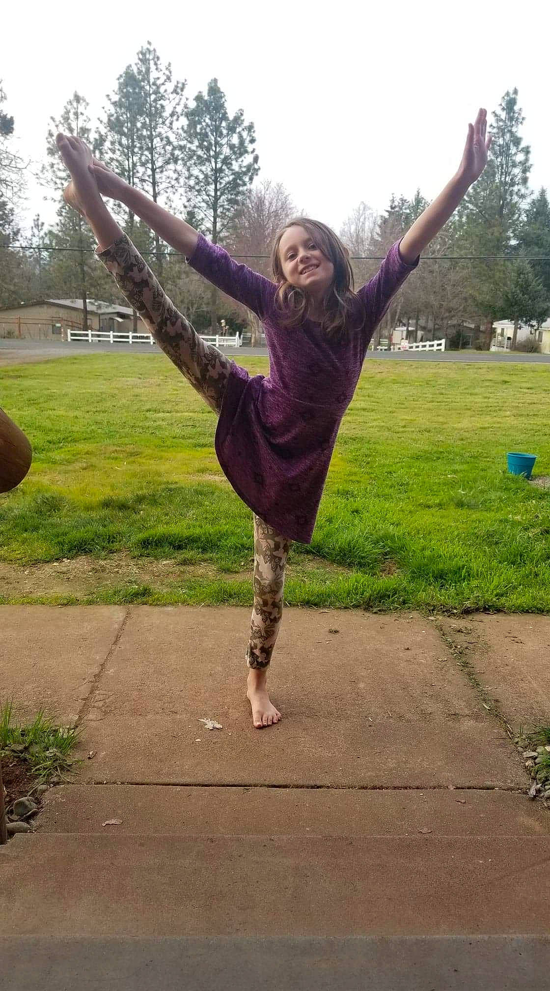 Zoey is registered to the contest to win money with this photo: balance, dance, flip_acrobatic, footwear, grass, happy, joy, jumping, leg, performance, person, physical_fitness, smile, sportswear, stretching, tree