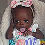 baby, child, infant, tongue_out, headband, bow, pink, donut, colorful_clothing, first_birthday, cute, playful, smiling, portrait, soft_texture, fluffy, happy, young_child, person, indoors